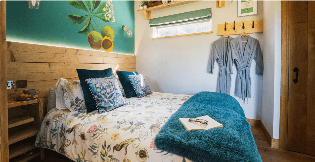 The Roost Glamping Nook bed with book & glasses landscape